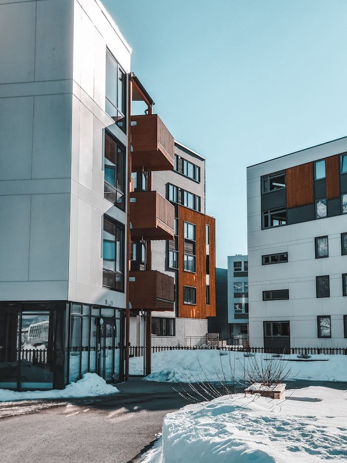 Contemporary apartment buildings with wooden accents in a snowy urban environment.